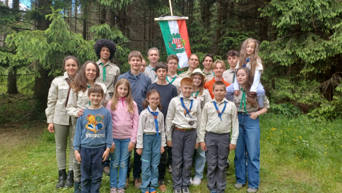 Egy 20 fős magyar cserkészcsapat vidám csoport képe a magyar lobogóval